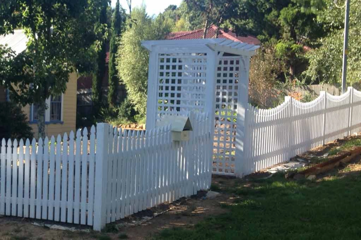 Crisp white scalloped picket fence with garden arbor